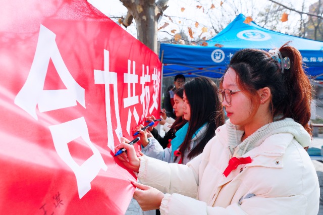 20231127中國石油大學(xué)（華東）青年學(xué)子在合力共抗艾滋的條幅上簽字，表達(dá)抗擊艾滋病的決心和信心  .jpg